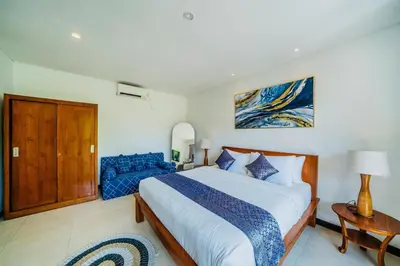 a bedroom with a large bed and a blue couch at Villa Julissa in Seminyak