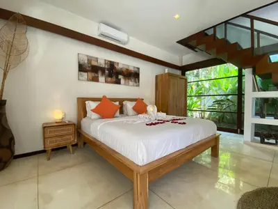 a bedroom with a bed with white sheets and orange pillows at Spacious Villa in Petitenget Top Location in Seminyak