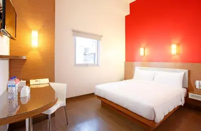 a bedroom with a bed and a table and a desk at Amaris Hotel Teuku Umar in Denpasar