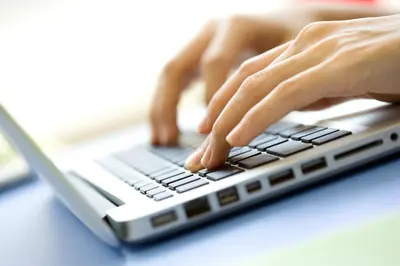 a person is typing on a laptop computer at Amaris Hotel Teuku Umar in Denpasar
