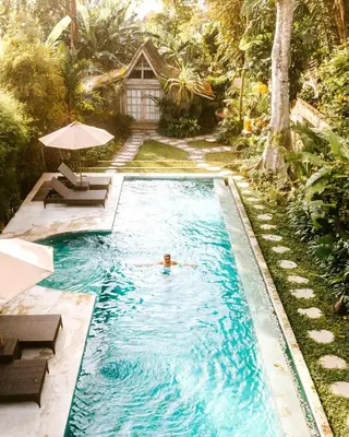 a person swimming in a pool in a backyard at Villa Adagian - Magical 3BR Villa in Umalas in Canggu