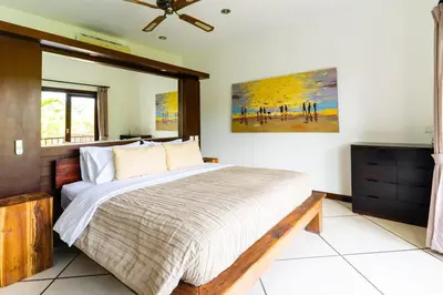 a bedroom with a bed and a painting on the wall at Virginia villa 4BR 5min walk to beach with assistant villa and pick up from airport and security in Canggu