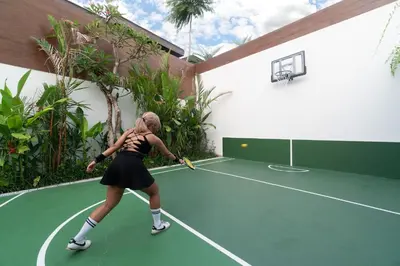 a woman playing tennis on a tennis court at Villa Marlex by Bukit Vista in Seminyak