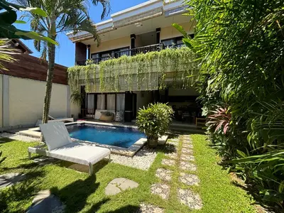 a backyard with a white chair and a swimming pool at Kubu D Kubu Villa - 3 Bedroom - Legian in Legian