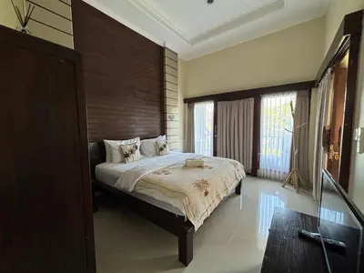a bedroom with a large bed with a wooden headboard at Kubu D Kubu Villa - 3 Bedroom - Legian in Legian