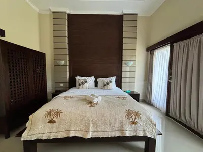 a bedroom with a large bed with a wooden headboard at Kubu D Kubu Villa - 3 Bedroom - Legian in Legian