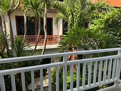 a white fence in front of a house with palm trees at HomelyBali, Cozy studio in Rajapala! in Seminyak