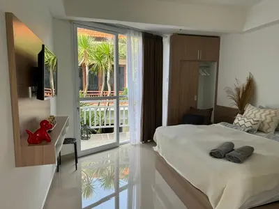 a bedroom with a bed and a view of a balcony at HomelyBali, Cozy studio in Rajapala! in Seminyak