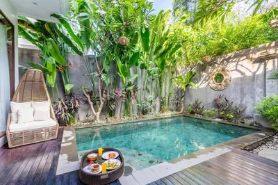 a small swimming pool in a garden with a chair at Villa Sun Lila by JB Villas in Seminyak