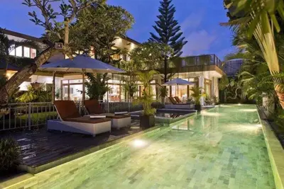 a house with a swimming pool with chairs and umbrellas at Tranquil Classic Balinese Villa in Badung