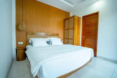 a bedroom with a large white bed with a wooden wall at Pradha Kuta, 3 BDR, 3 minutes from seminyak beach in Seminyak