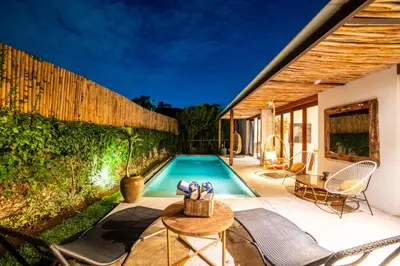 a swimming pool in a backyard with chairs and a table at Anggana Villa 3 in Canggu