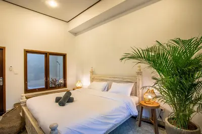 a bedroom with a bed and a potted plant at Villa Shiro in Seminyak