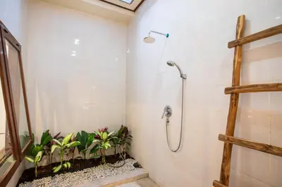 a bathroom with a shower with plants in it at Villa Shiro in Seminyak