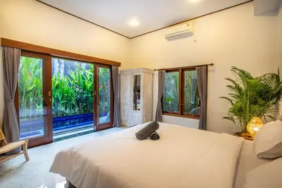 a bedroom with a large bed and large windows at Villa Shiro in Seminyak