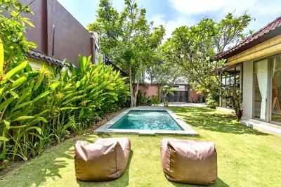 a backyard with a swimming pool and two chairs at Mantra Dom Villa 3 Bedrooms in Canggu