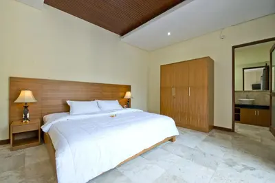 a bedroom with a large white bed and a bathroom at Seminyak Villa in Seminyak