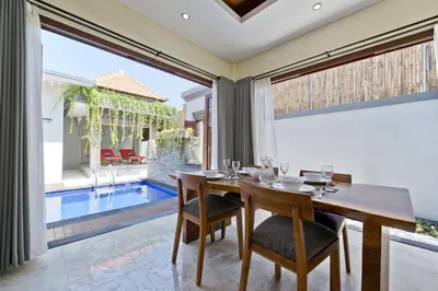 a dining room with a table and chairs and a pool at Seminyak Villa in Seminyak