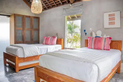 a bedroom with two beds and a window at Villa Marie Clare in Seminyak