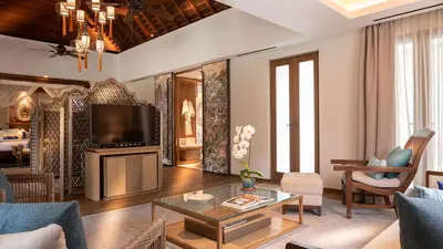 a living room with a couch and a tv at Des Indes Villas in Seminyak