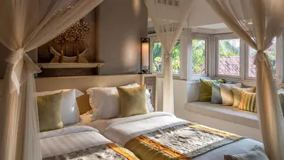 a bedroom with a bed with curtains and a window at Des Indes Villas in Seminyak