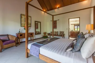 a bedroom with a large bed and a chair at 2 Bedroom Private Pool walking distance to the Seminyak beach in Seminyak