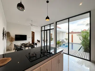 an open kitchen and living room with a view of a pool at Kubung 1 - Villa with HUGE Pool and PS5 in Kerobokan