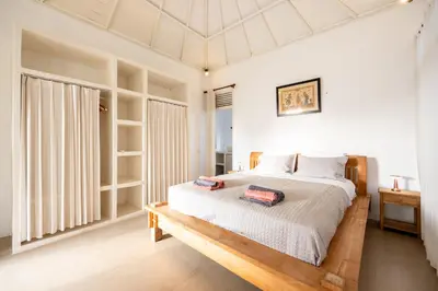 a bedroom with a large bed with a wooden frame at Villa Selamat, Seminyak, Batu Belig, 10 min from beach in Seminyak