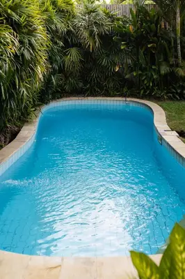 a large blue swimming pool with trees in the background at Villa Selamat, Seminyak, Batu Belig, 10 min from beach in Seminyak
