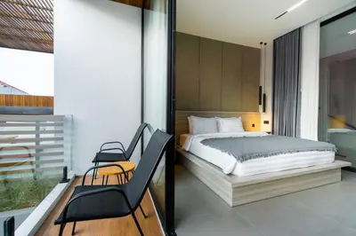 a bedroom with a bed and two chairs on a balcony at Villa Elena by Maheswara in Seminyak