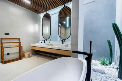 a bathroom with a tub and a sink and mirrors at Villa Elena by Maheswara in Seminyak