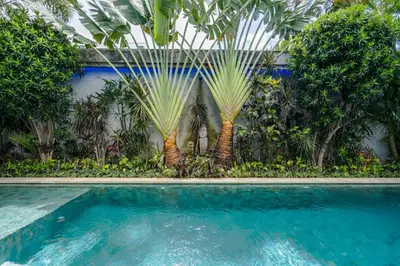 a swimming pool with palm trees in the background at Villa Céline 1 Bdr pool Seminyak in Seminyak