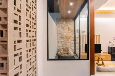 a living room with a stone wall with a fireplace at Vin Villa Seminyak 2BR with Private Pool in Seminyak