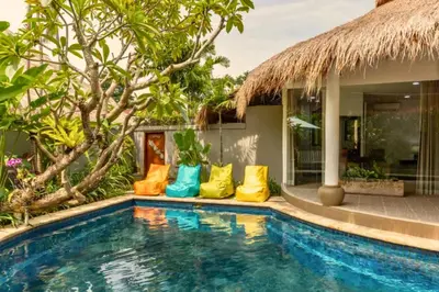 a pool with colorful pillows next to a house at Hazel Azalea 4 BR Private Pool Villa in Seminyak