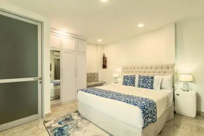 a white bedroom with a large bed and a bathroom at Hazel Azalea 4 BR Private Pool Villa in Seminyak