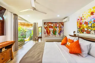 a bedroom with a large bed and a painting on the wall at House Lizard 3 BR Private Pool Villa in Kerobokan