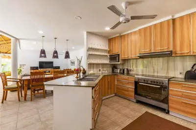 a kitchen with wooden cabinets and a dining room at House Lizard 3 BR Private Pool Villa in Kerobokan