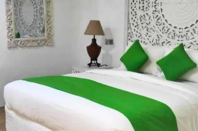 a white bed with green pillows in a bedroom at House Lizard 3 BR Private Pool Villa in Kerobokan