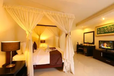 a bedroom with a canopy bed and a television at Lavender 1 BR Private Pool Villa in Seminyak