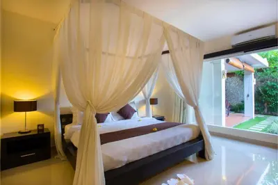 a bedroom with a canopy bed and a large window at Ageratum 4 BR Villa Private Pool in Seminyak