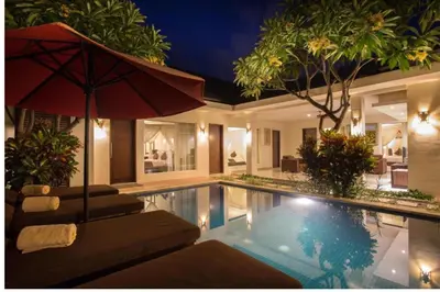 a swimming pool with an umbrella and a house at Ageratum 4 BR Villa Private Pool in Seminyak