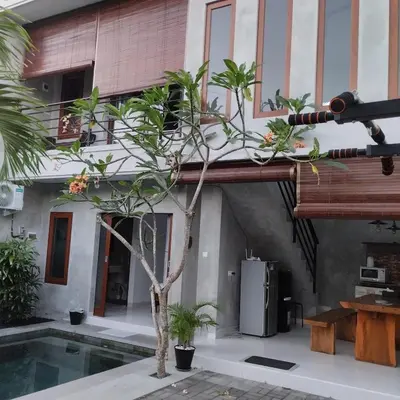 a house with a tree in front of a swimming pool at Jimbaran Beauteous Villa in Jimbaran