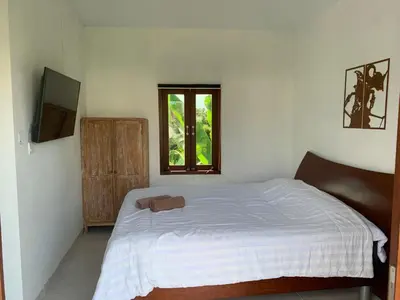 a bedroom with a white bed and a window at Jimbaran Beauteous Villa in Jimbaran