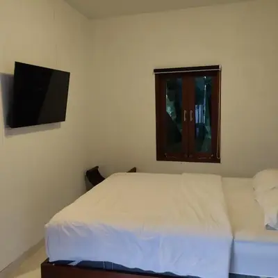 a bedroom with a white bed and a television at Jimbaran Beauteous Villa in Jimbaran