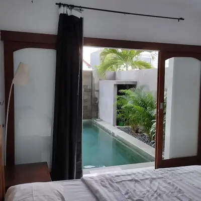 a bedroom with a view of a swimming pool at Jimbaran Beauteous Villa in Jimbaran