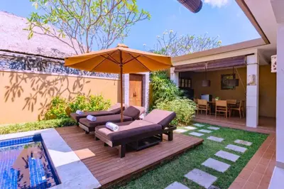 a patio with two couches and an umbrella at Dahlia Mentari 2 BR Private Pool Villa in Seminyak
