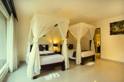 a bedroom with two beds with mosquito nets at Allamanda 3 BR Private Pool Villa in Seminyak