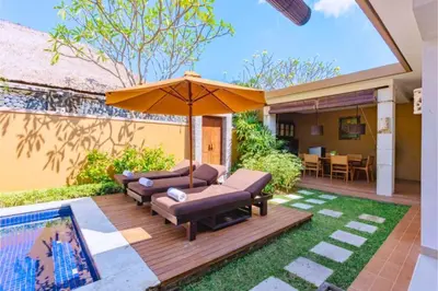 a patio with two couches and an umbrella at Allamanda 3 BR Private Pool Villa in Seminyak