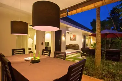 a dining room with a table with chairs and lights at Allamanda 3 BR Private Pool Villa in Seminyak
