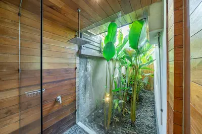 a bathroom with a stone wall and a plant at Villa Ayuni, Berawa in Canggu
